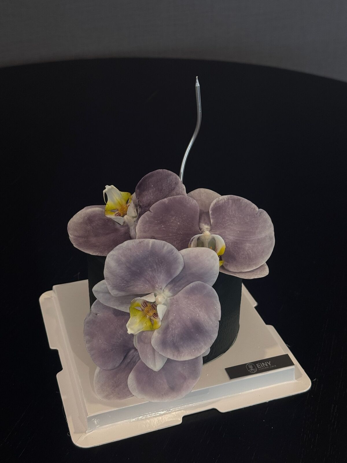 Dark cake with a cascade of lilac sugar orchids